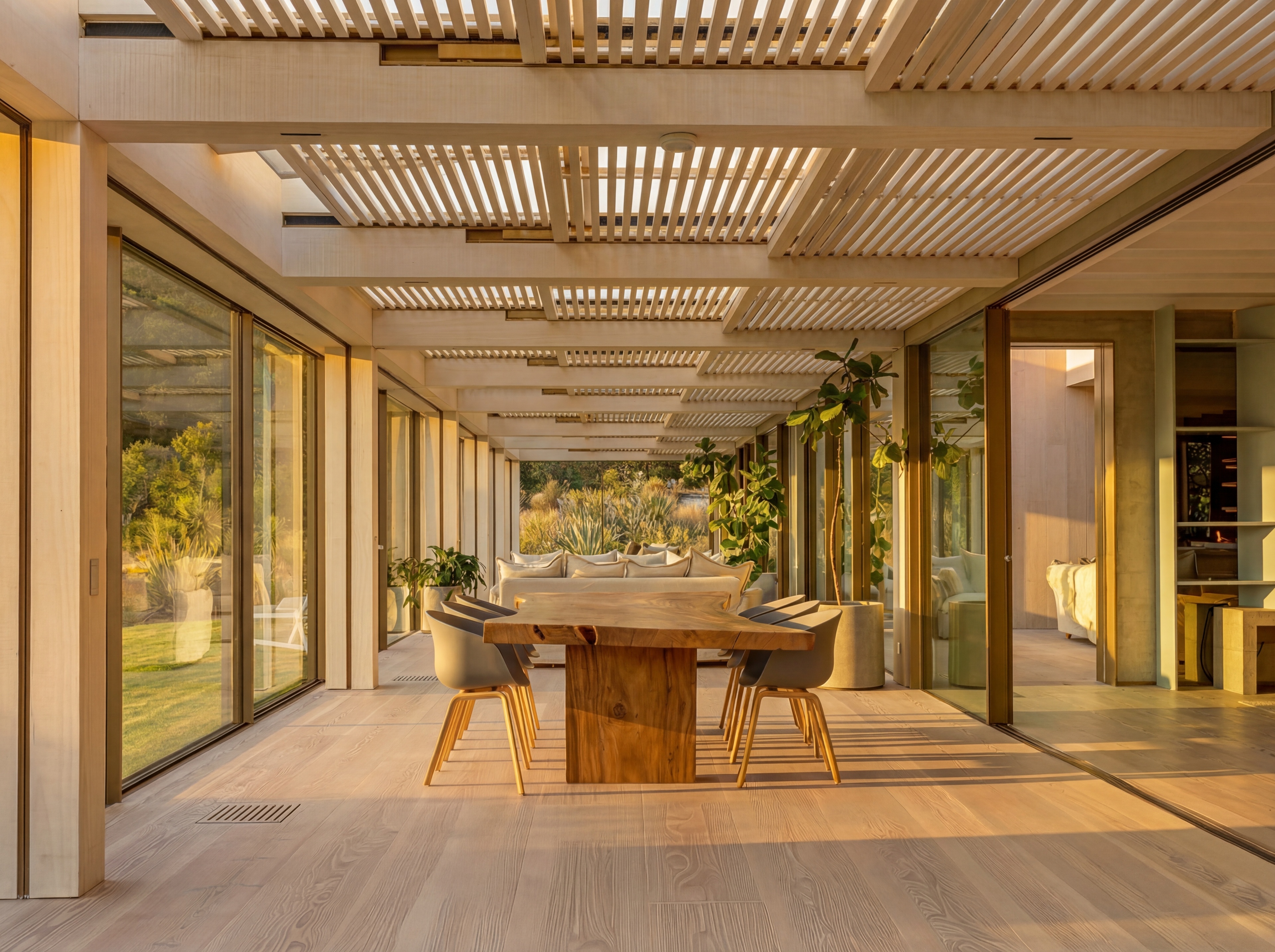 Dining area within the conservatory with slatted timber ceiling and garden views